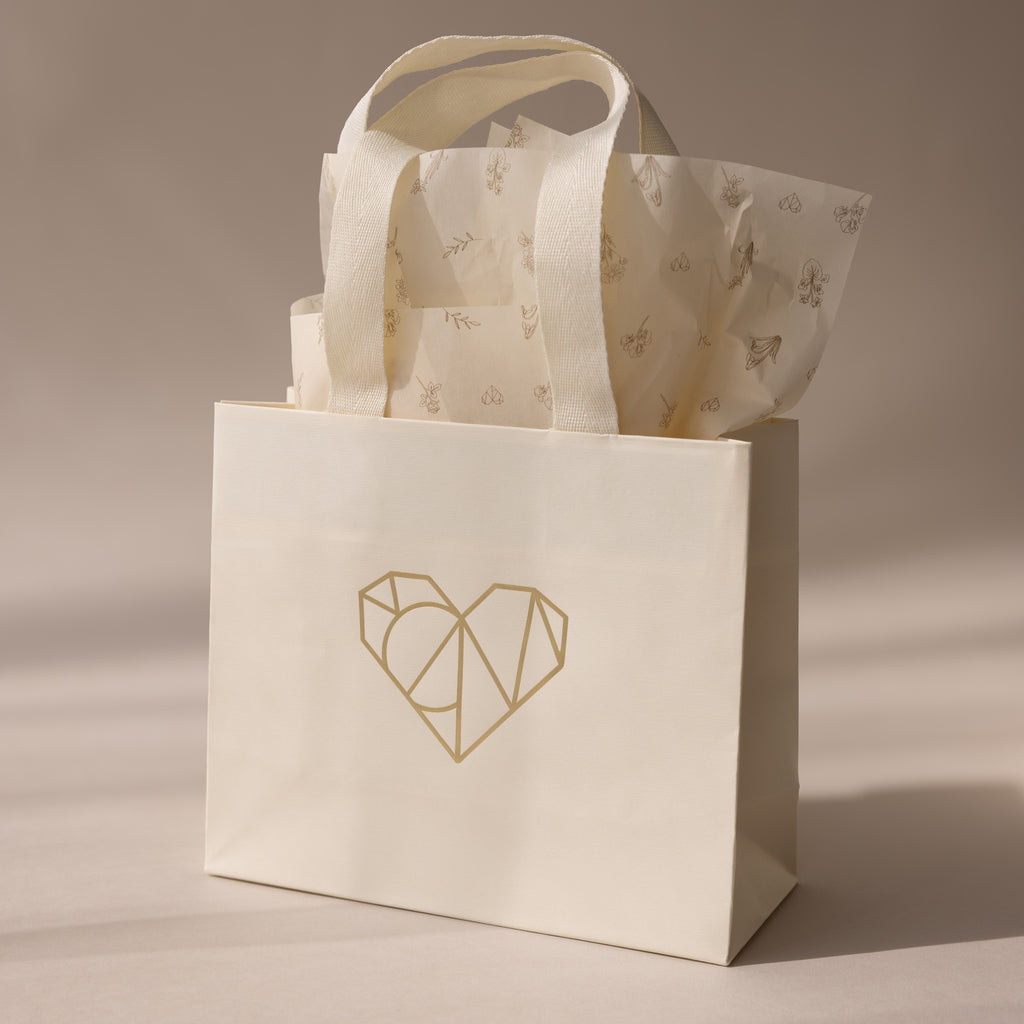 The Gift Bag Add-On features a cream hue with a geometric heart design and patterned tissue paper—an elegant way to wrap gifts and add a special touch.