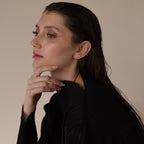 Woman with wet, dark hair in a black top gazes thoughtfully to the side, her look elegantly accented by Marquise Diamond Climbers in 18K Gold.