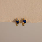 Sapphire Heart Hoops—gold earrings with blue heart-shaped stones and small clear gems—are perfect birthstone earrings to add elegance to any look.