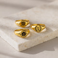Three College Emblem Signet Rings with engraved law school emblems are displayed on a light stone surface—an ideal graduation gift to celebrate achievement.