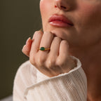 A woman rests her chin on her hand in soft natural light, showcasing the elegant Oval Jade Signet Ring.
