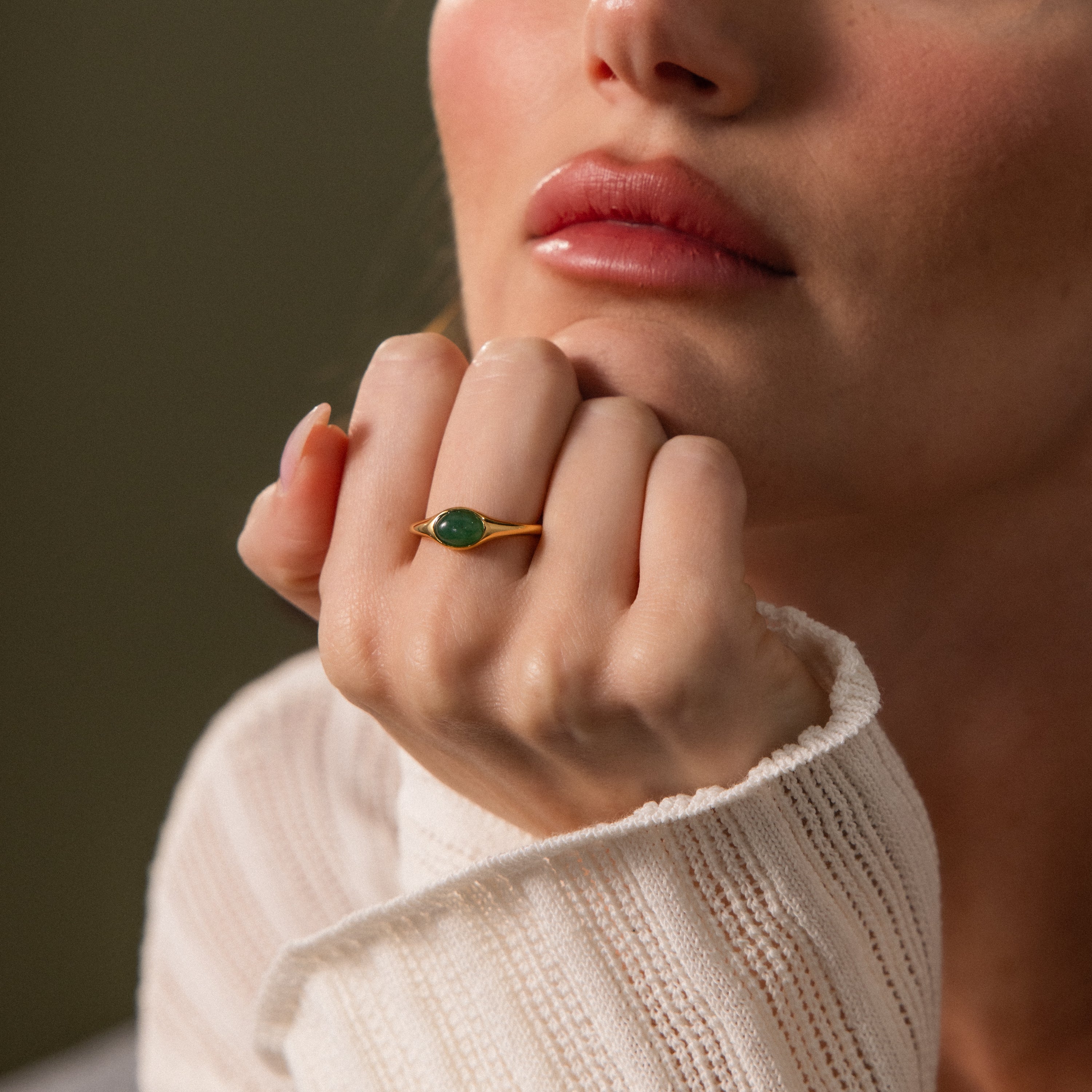 A woman rests her chin on her hand in soft natural light, showcasing the elegant Oval Jade Signet Ring.