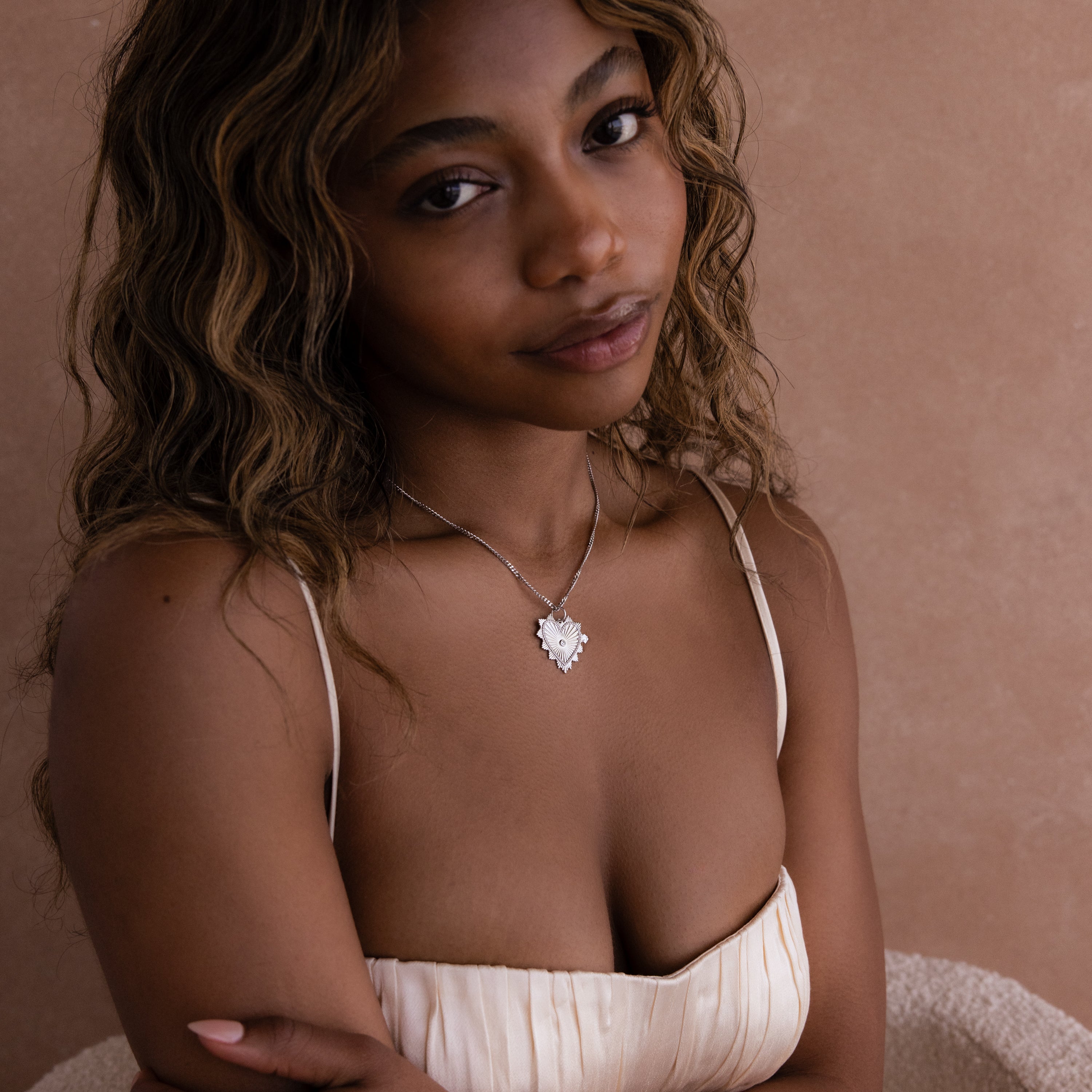 Model wears a curb chain with a white gold ribbed vintage heart charm