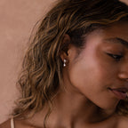 Close-up of a woman with wavy hair facing slightly right, wearing Heart Pearl Drop Earrings.