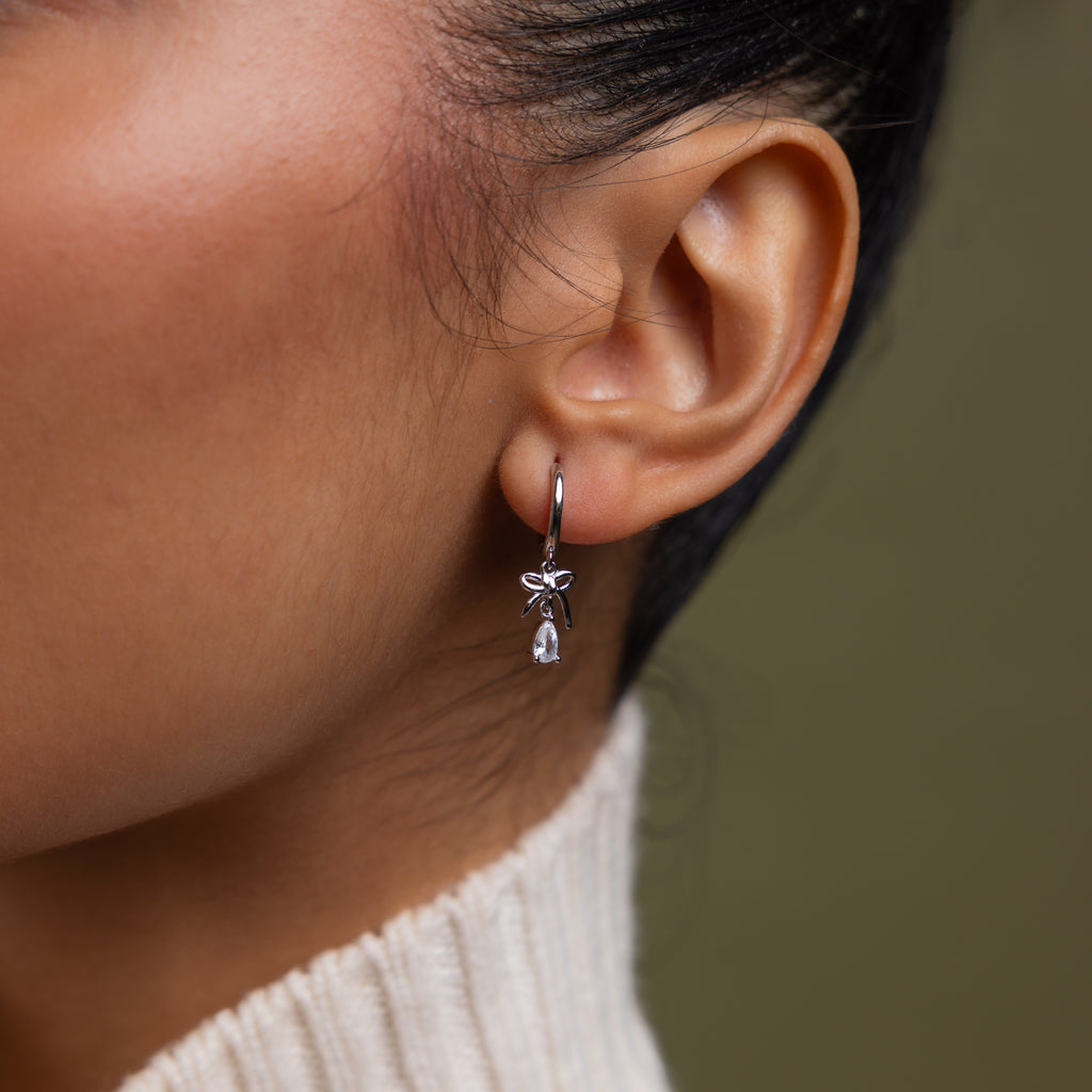 Close up of model wearing our Teardrop Ribbon Charm Hoops in Silver