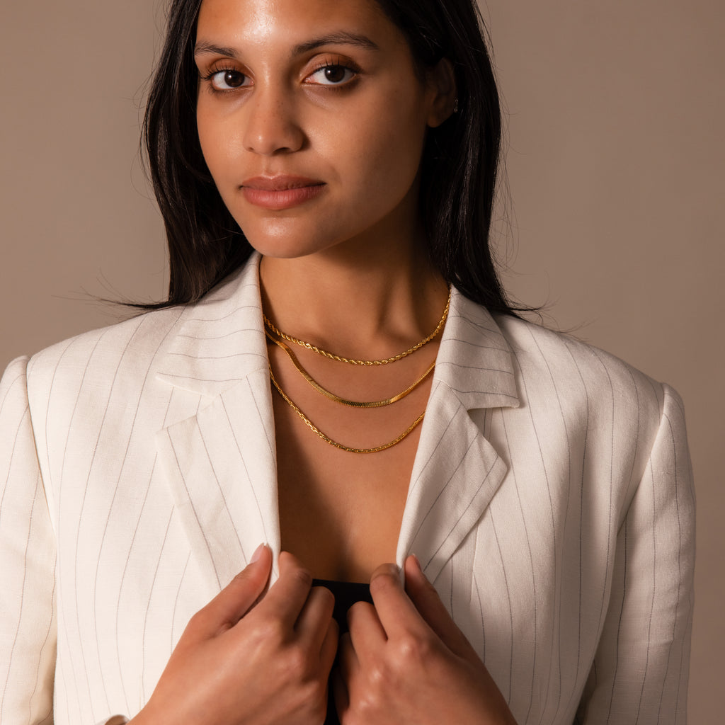 Woman in a white pinstripe blazer faces the camera with a neutral expression, wearing the Bold Link Chain Necklace layered over her outfit.