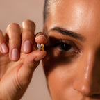 A woman holds a Pave Dome Charm in Silver close to her eye, its sparkle highlighting every detail against her face, reminiscent of a charm stack.