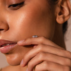 A woman’s face in profile with her hand near her lips, showcasing the Pave Dome Charm in Silver, a ring that adds a touch of sparkle.