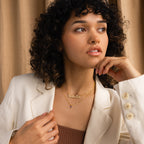 Woman with curly hair in a white blazer, wearing the Pave Dream Script Name Necklace and looking to the side.