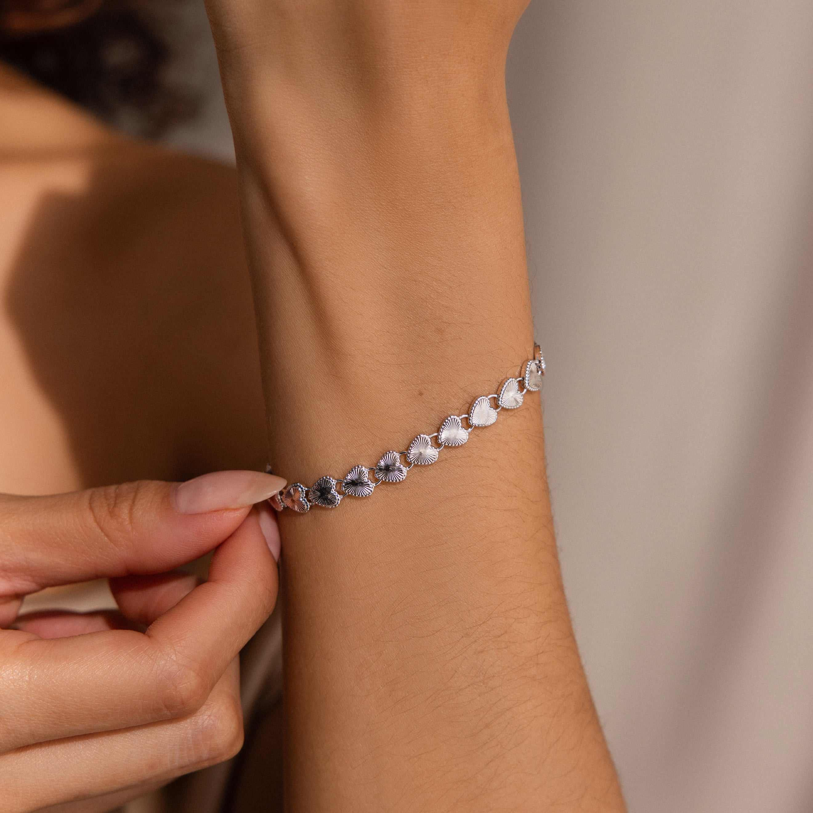 A graceful wrist shot of the Ribbed Heart Link Bracelet in White Gold. 