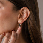 Close-up of a woman wearing Bold Teardrop Earrings in White Gold, gently touching her neck.