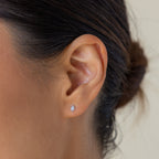 Close-up of a woman's ear wearing Ericka Diamond Studs; her hair is styled in a bun, highlighting the chic, minimalist appeal of these geometric earrings.