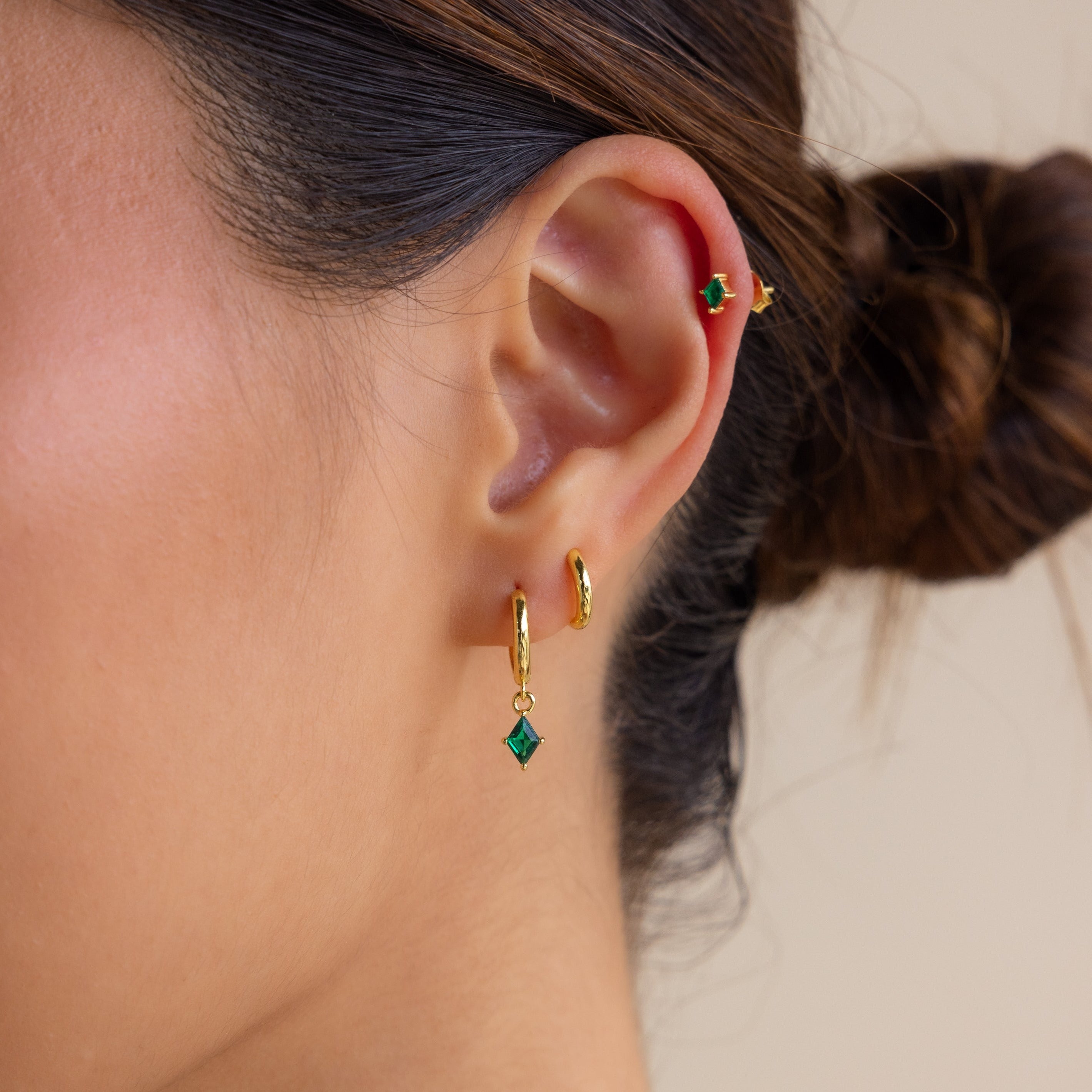 A close-up of a woman's ear showcasing the elegant Emerald Earrings Set.