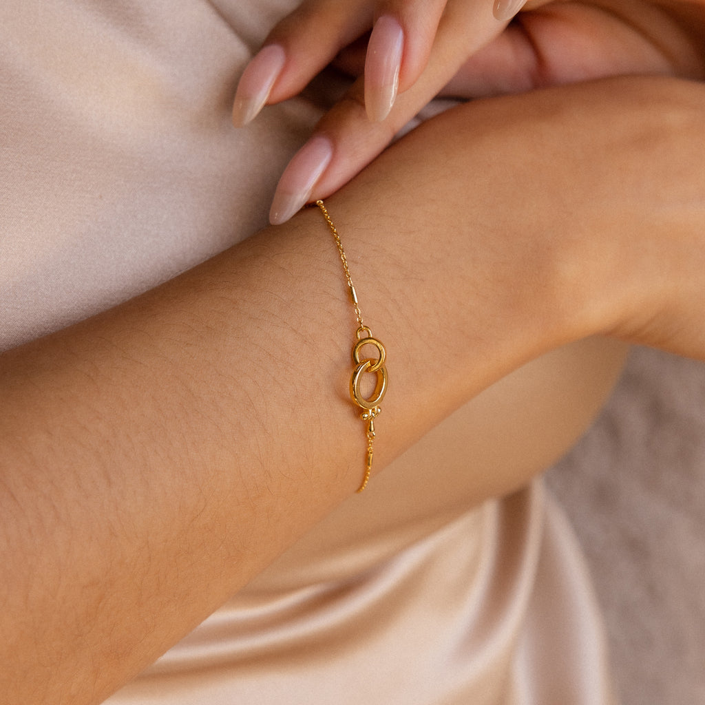 A close-up of the Hinged Circle Charm Bracelet featuring interlocking loops on a woman's wrist, highlighting her manicured nails.