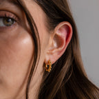 A close-up shows part of a woman's face and brown hair as she wears Beaded Hoops, highlighting the polished beads.