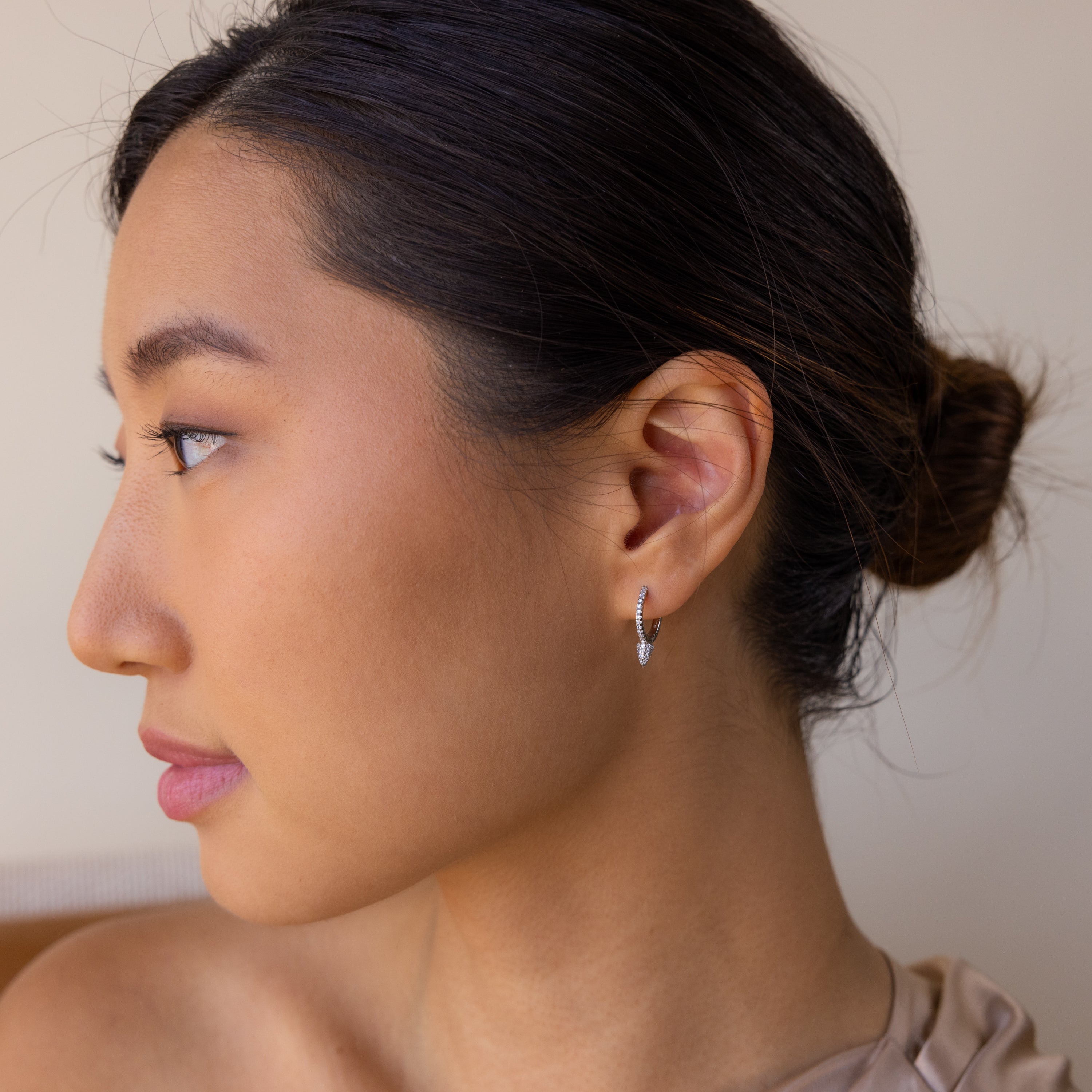 A woman with a bun in her hair wears Pave Spike Huggies, highlighting their edgy cone shape and sparkling pavé-set design.
