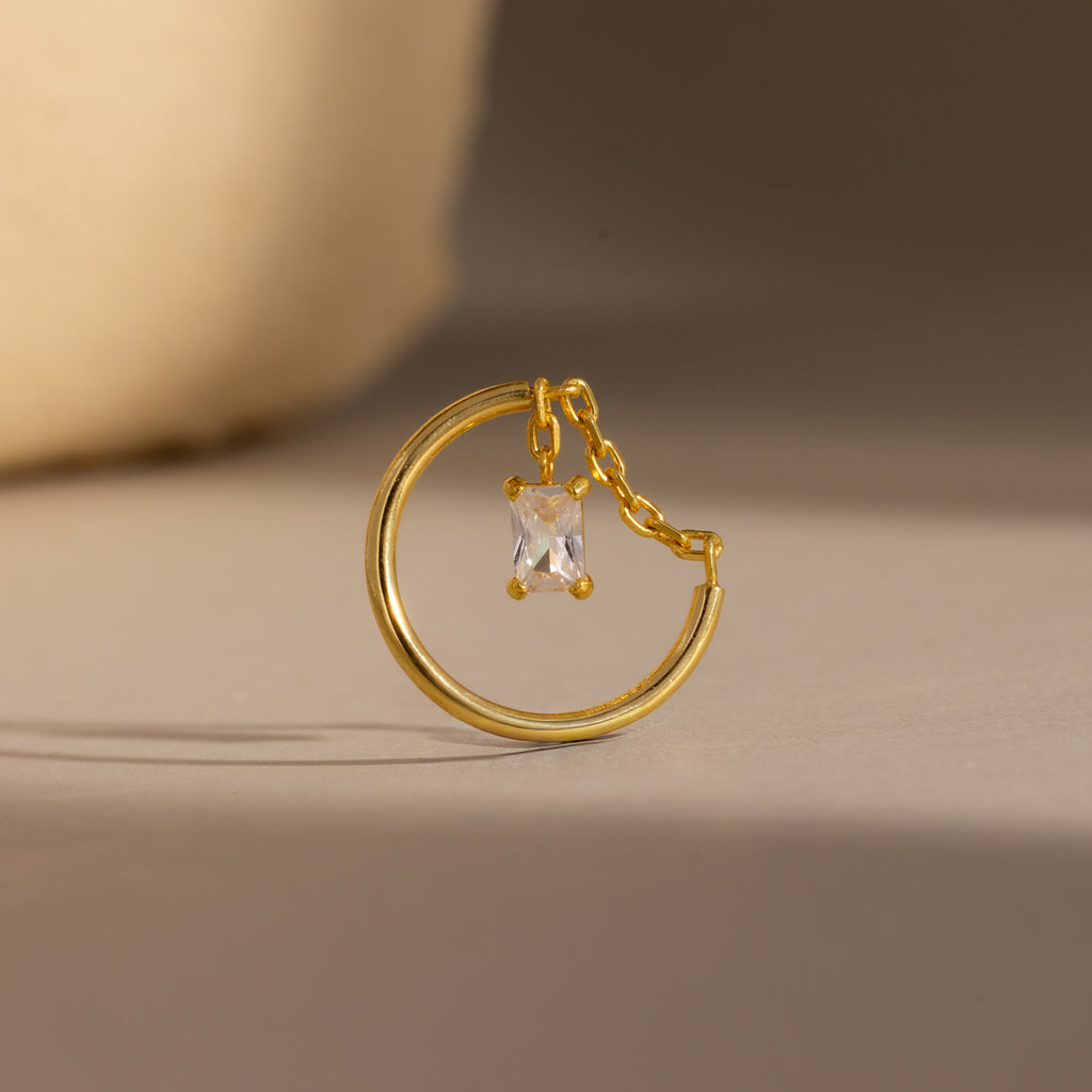 Opal Drop Chain Ring featuring a gold hoop with a small chain and a rectangular, emerald-cut opal pendant, displayed on a neutral background.