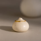 The Opal Half Chain Ring is a delicate gold ring featuring a small diamond, shown on a smooth, round white ceramic object.