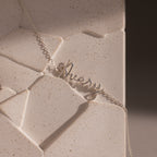 Cursive Name Bracelet in Sterling Silver featuring the name Avery, showcased on a textured beige stone background to highlight the elegance of personalized jewelry.