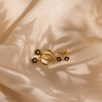 Onyx Flower Studs in 18K Gold with black onyx accents are displayed on cream-colored textured fabric, casting soft shadows.
