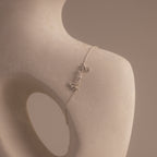 The Cursive Name Bracelet in Sterling Silver displays the word "merci" in elegant script, gracefully draped on a smooth, abstract sculpture featuring a round opening.