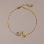 The Cursive Name Bracelet in 18K Gold features "Emily" in elegant script on a neutral background—a perfect personalized gift for custom name jewelry lovers.