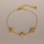 The Pearl Clover Letter Bracelet in 18K Gold features three white mother of pearl clover charms with the letters M, R, and S on a neutral background.