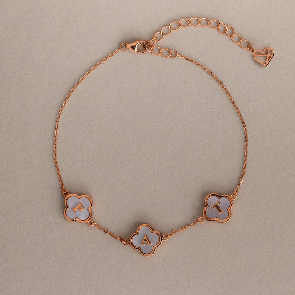 The Pearl Clover Letter Bracelet in Rose Gold features three white mother of pearl clover charms, each with a letter: B, A, and T.