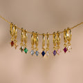Nine Birthstone Drop Huggies featuring colorful gemstone charms on thin gold chains, perfect for personalized jewelry. Displayed against a neutral background.
