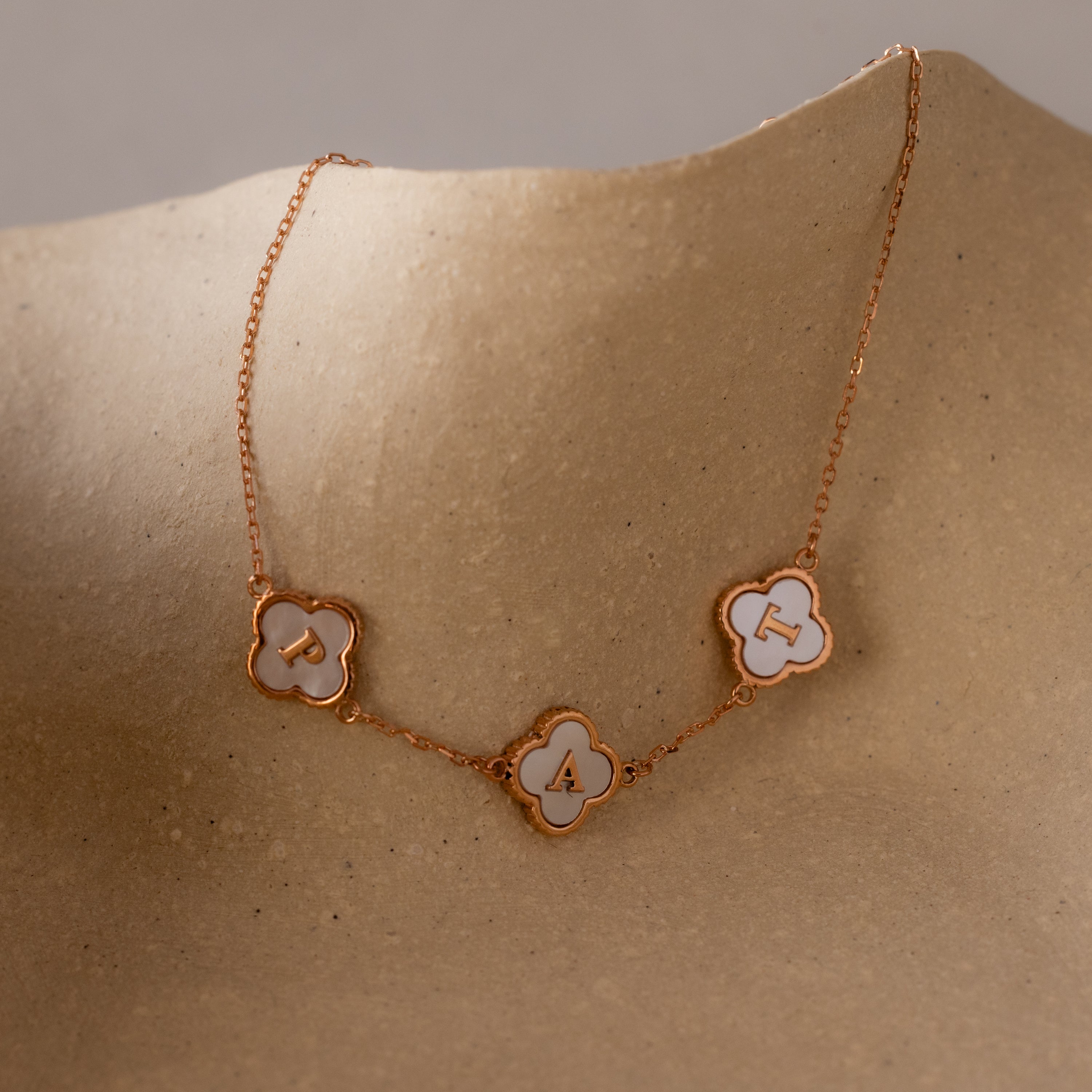 The Pearl Clover Letter Bracelet in Rose Gold features three clover-shaped mother of pearl charms, each charm displaying the letters P, A, and T.