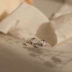 Butterfly Drop Huggies in Sterling Silver with small gemstones and diamond accents displayed on soft beige fabric with gentle shadows.