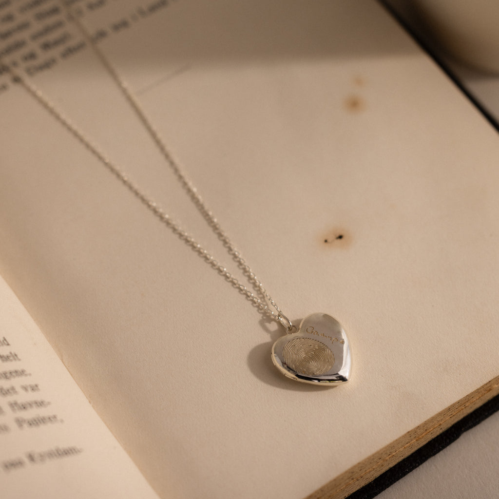 Flatlay of our our Fingerprint Heart Locket Necklace in Silver