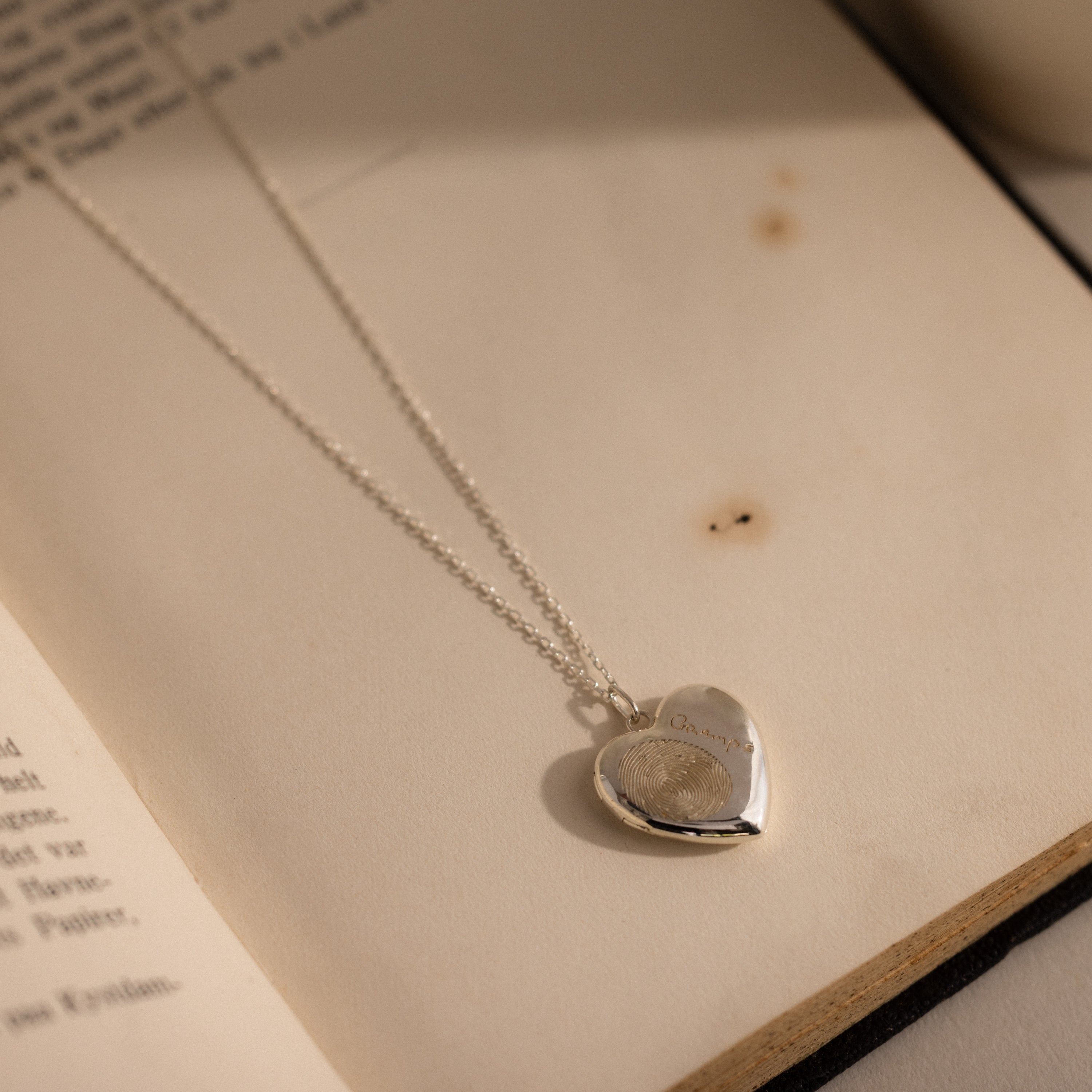 Flatlay of our our Fingerprint Heart Locket Necklace in Silver