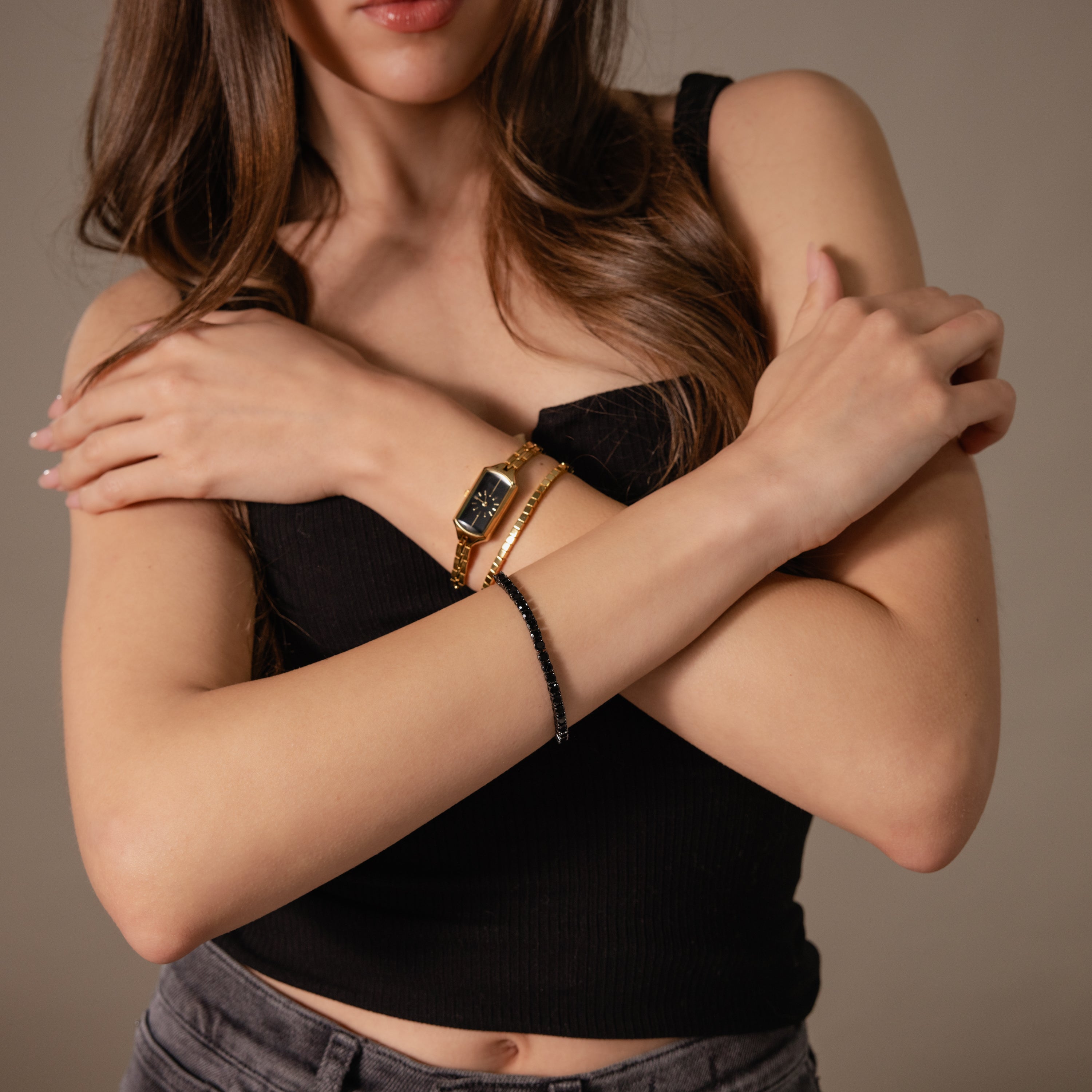 Woman in a black tank top crossing her arms, wearing a watch and the Onyx Tennis Bracelet.