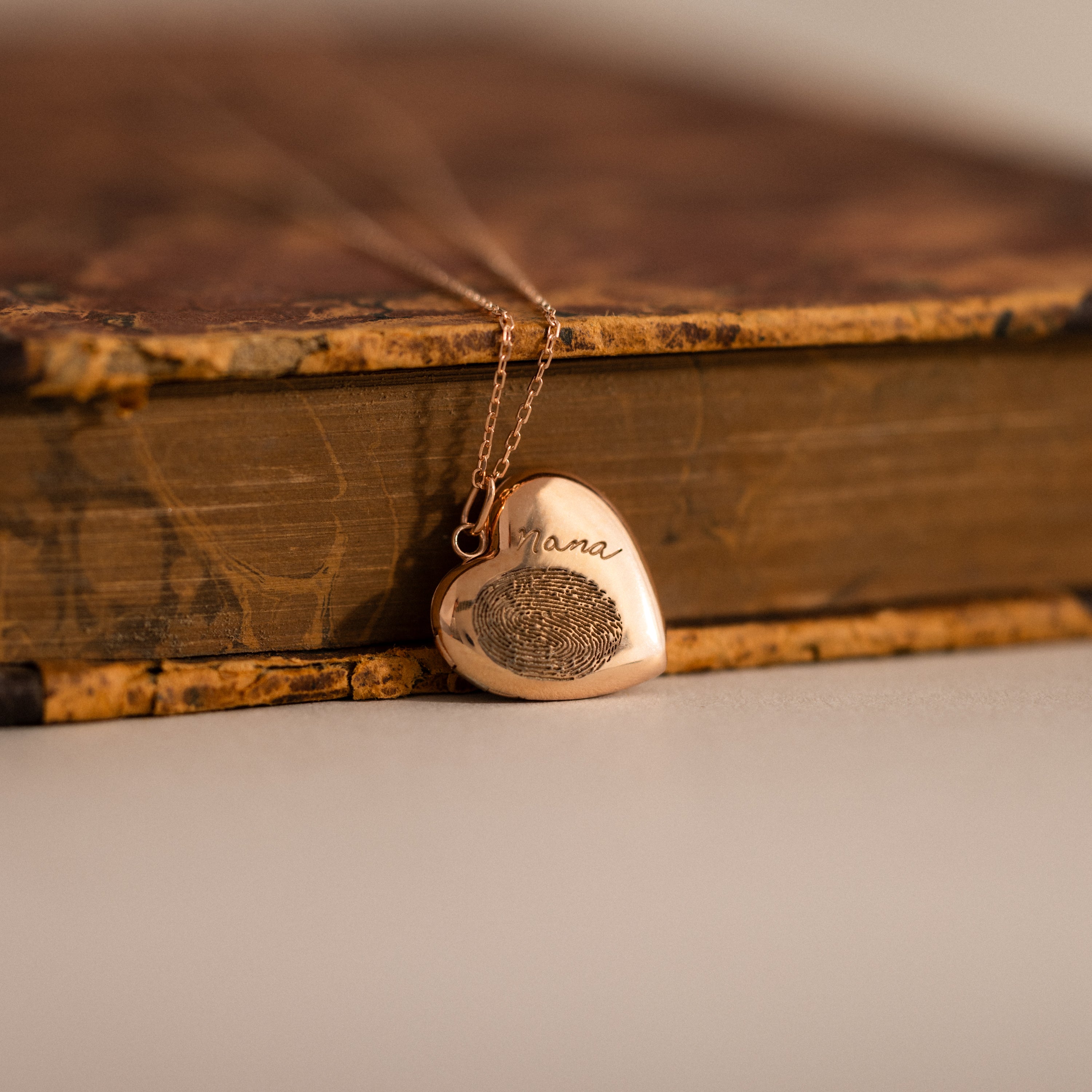 Close up flatlay of our Fingerprint Heart Locket Necklace in Rose Gold