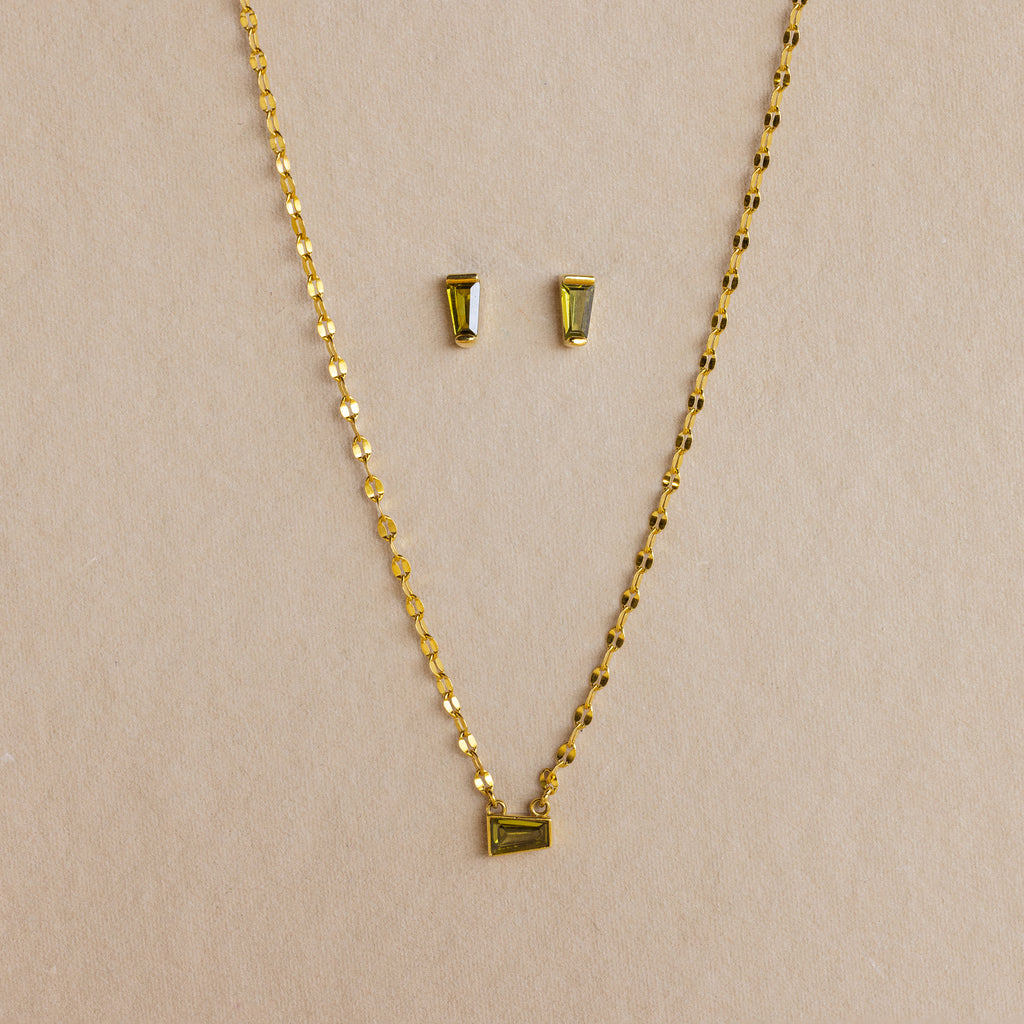 Tapered Baguette Birthstone Studs and a gold chain necklace with a rectangular pendant are displayed together against a neutral background.