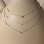 The Initial Baguette Birthstone Necklace—available in gold, silver, and rose gold—is showcased on a white mannequin bust.