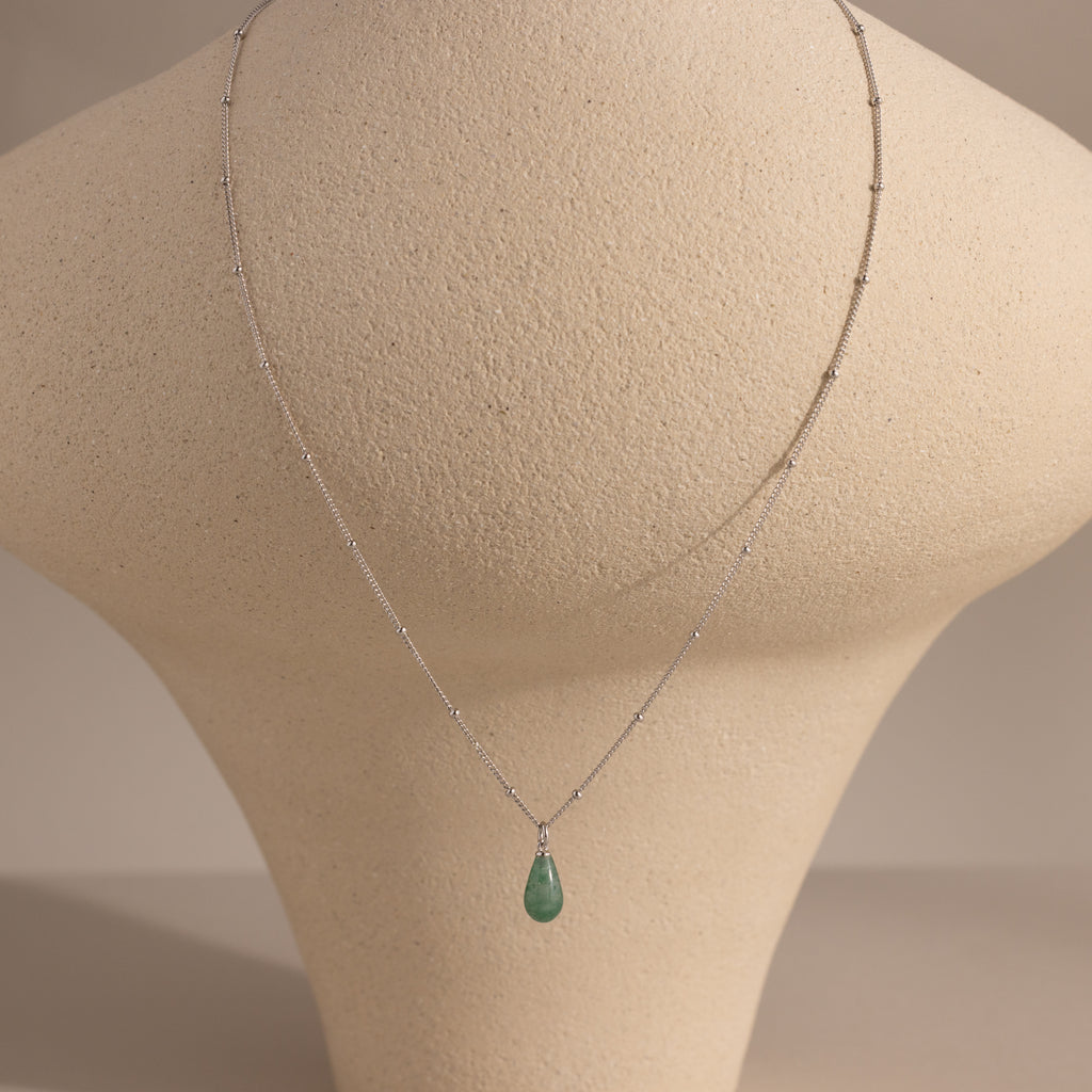Silver satellite chain necklace featuring a single green jade teardrop gemstone pendant displayed on a neutral bust prop.