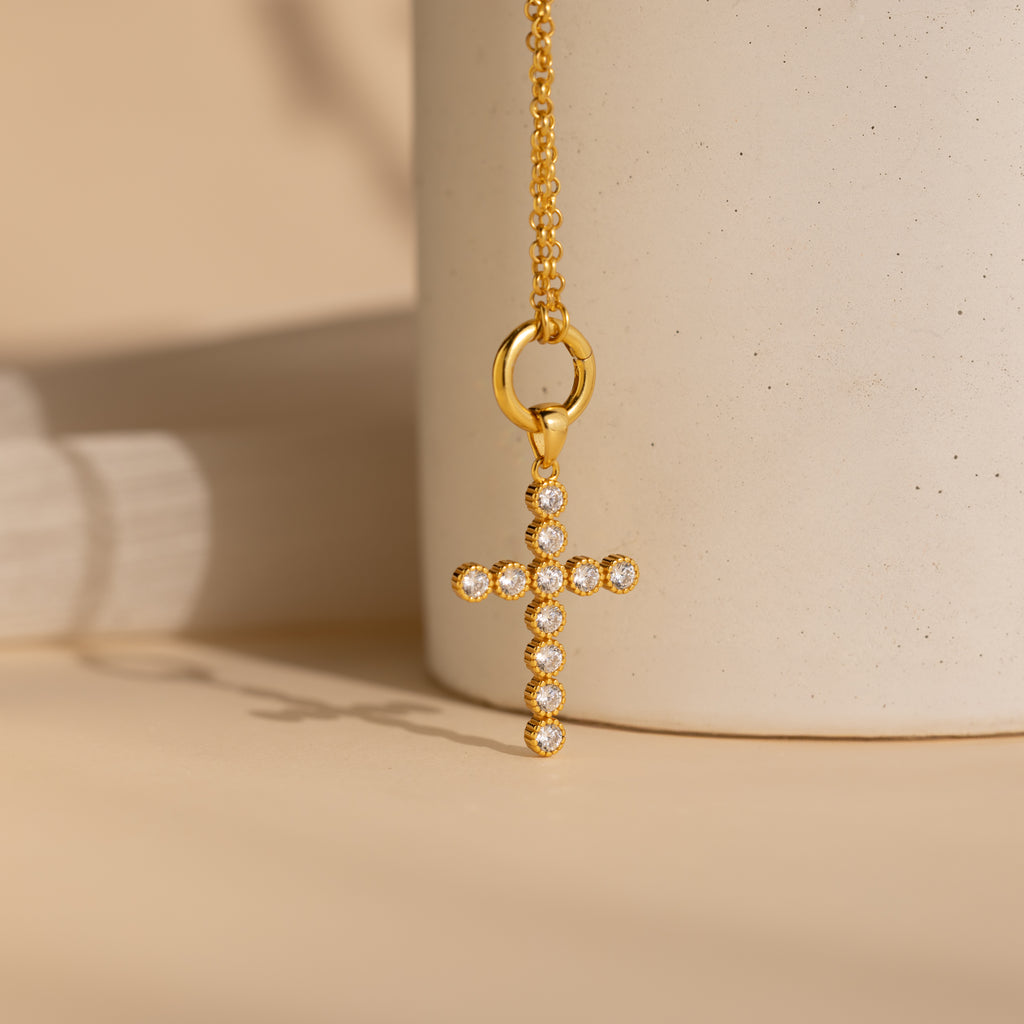 A gold pave cross charm hangs from a gold rolo circle necklace
