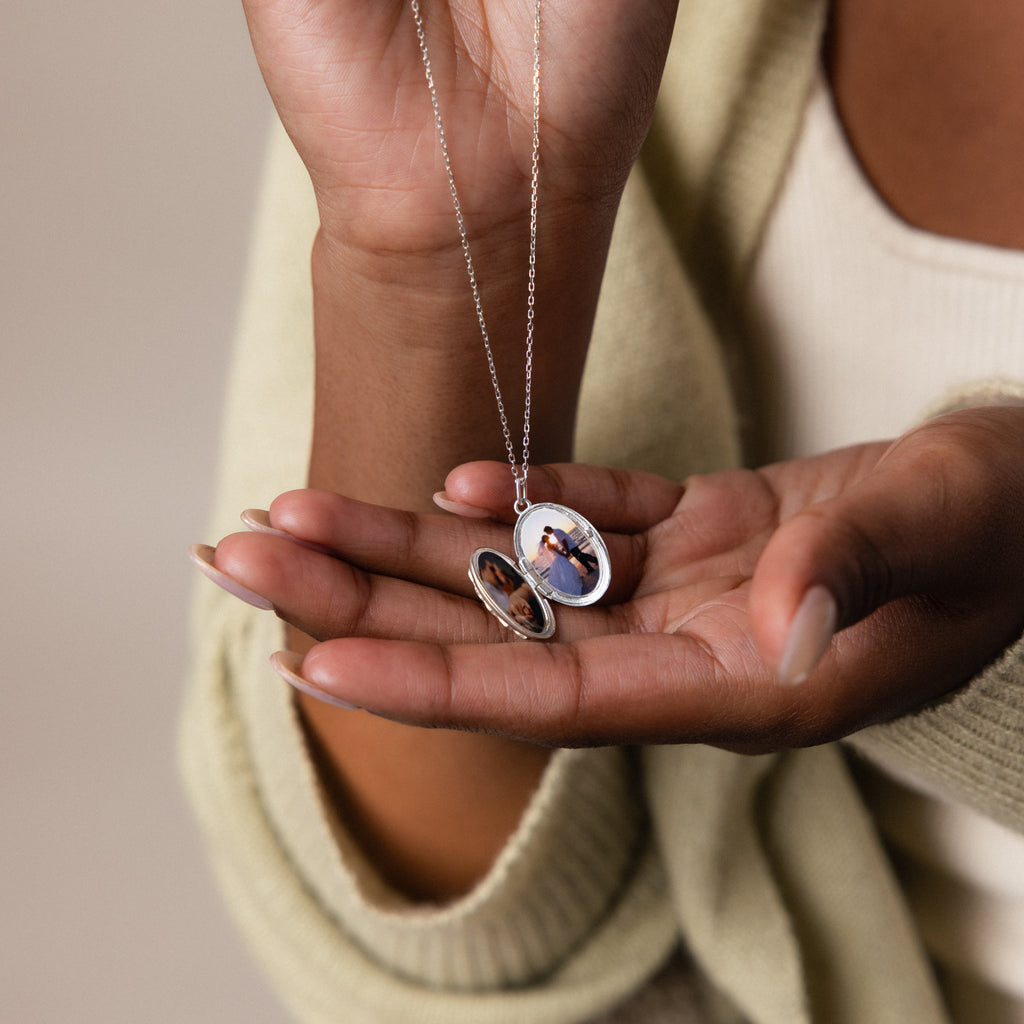 A person holds an open Floral Handwriting Locket Necklace, revealing a small photo tucked inside.
