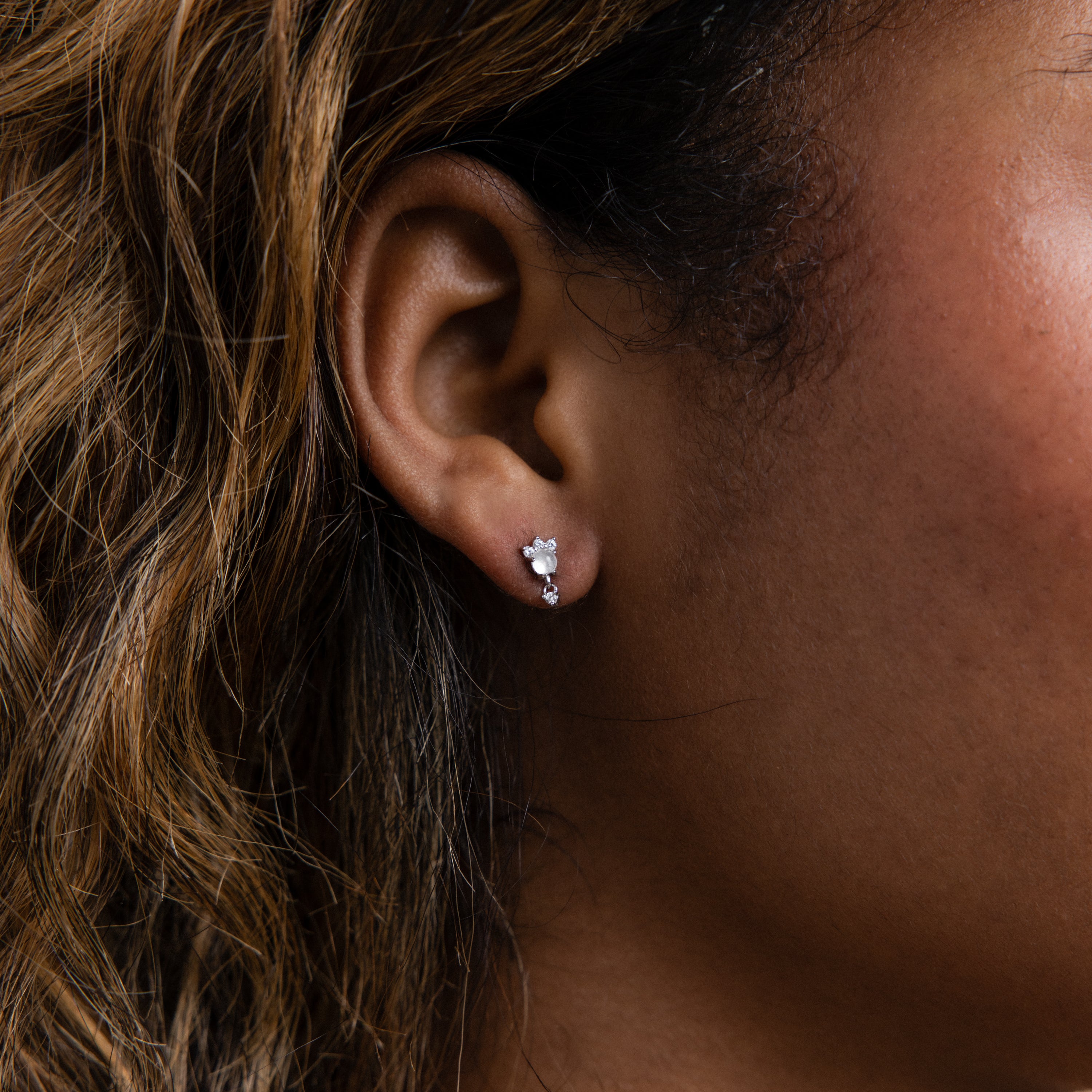 Close-up of a woman's ear wearing Halo Moonstone Drop Studs—small, elegant, and perfect for pairing with other drop earrings or diamond studs to create a chic, layered look.