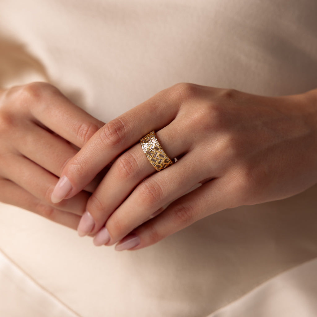 Close-up of hands with manicured nails wearing the Mosaic Diamond Baguette Ring, showcasing its wide band and intricate patterned design on the ring finger.