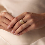 Close-up of hands with manicured nails wearing the Mosaic Diamond Baguette Ring, showcasing its wide band and intricate patterned design on the ring finger.