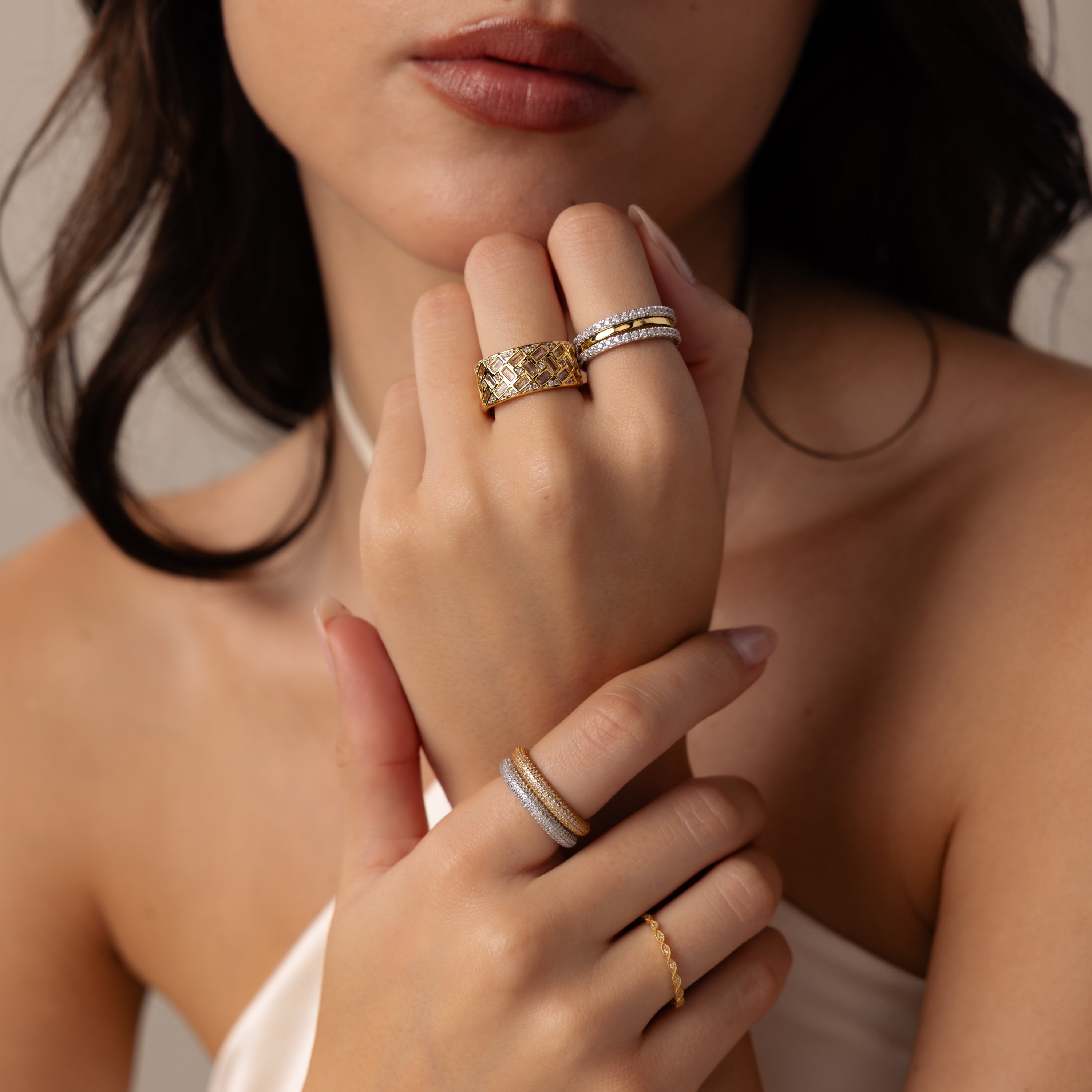 A woman’s hands showcase a striking Mosaic Diamond Baguette Ring paired with silver wide band rings, with a close-up focus on her jewelry.