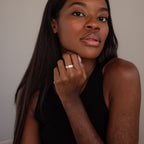 A woman with long hair in a black top confidently displays the Ann Thin Message Ring in Sterling Silver on her hand while looking directly at the camera.