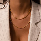A woman in a pinstriped blazer wears two layered gold necklaces, featuring the Bold Link Chain Necklace in 18K Gold for a modern, statement look.