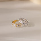 The Colette Eternity Ring in Silver, adorned with sparkling baguette diamonds, shines beautifully on a glossy surface—a true statement jewelry piece.
