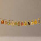 The Birth Flower Charm Necklace features a gold chain with twelve rectangular pendants, each showcasing a distinct colorful floral design—an elegant piece that brings artistic flair to any outfit.