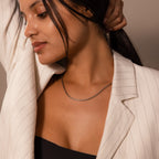 Woman in a white pinstripe blazer and black top wears the Bold Link Chain Necklace in Silver, looking down with one arm raised.