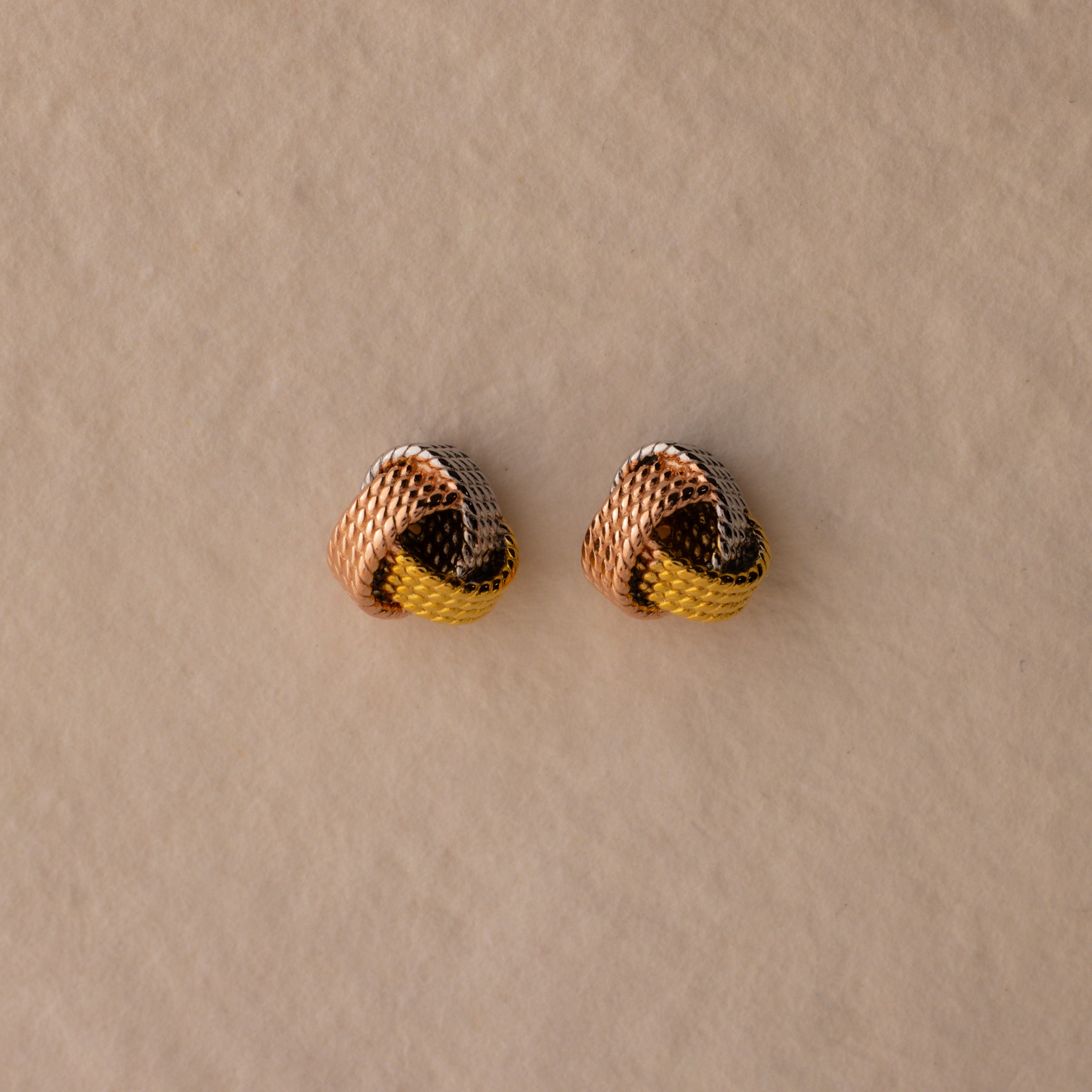 Rope Knot Studs in Mixed Metal feature elegant gold, silver, and rose gold tones, beautifully displayed on a beige background.